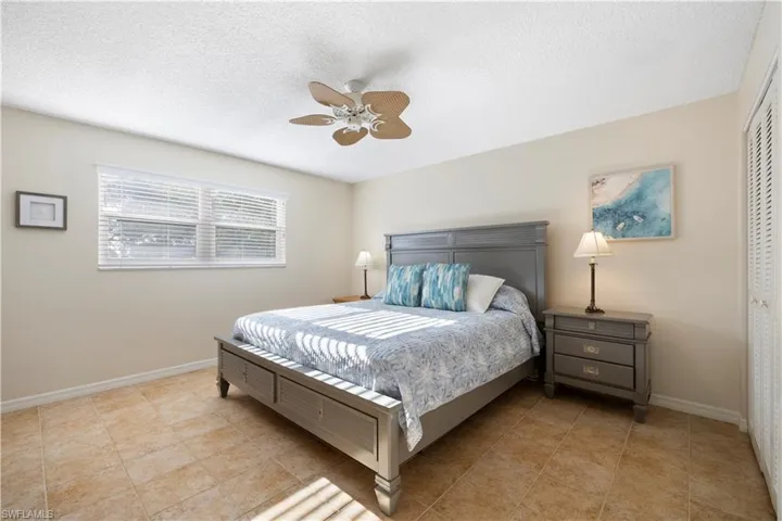 Bedroom featuring a textured ceiling, ceiling fan, a closet, and light tile patterned flooring