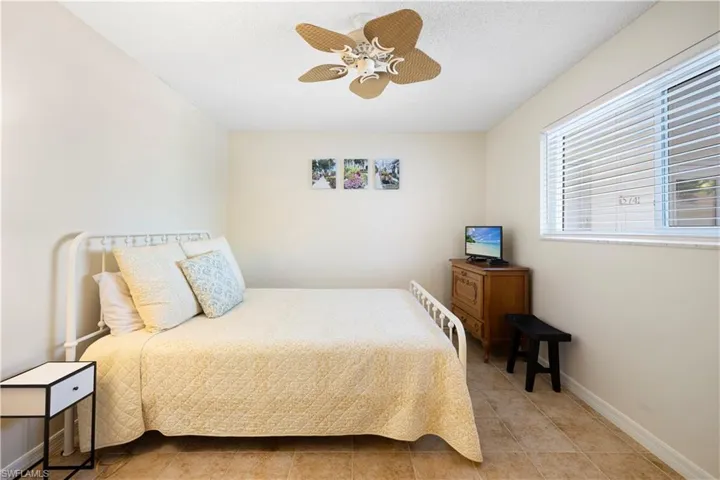 Bedroom with ceiling fan, tile patterned flooring, and a textured ceiling