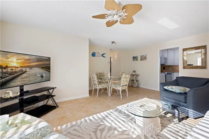 Living room featuring light tile patterned flooring, ceiling fan, and a textured ceiling