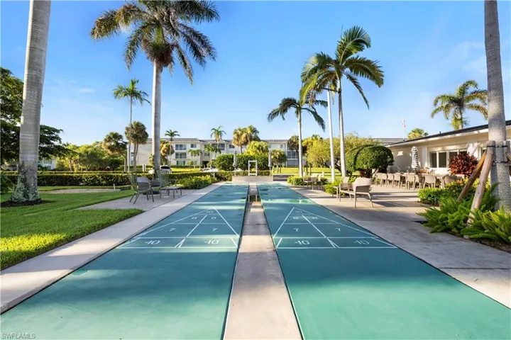 View of property's community with shuffleboard and a yard