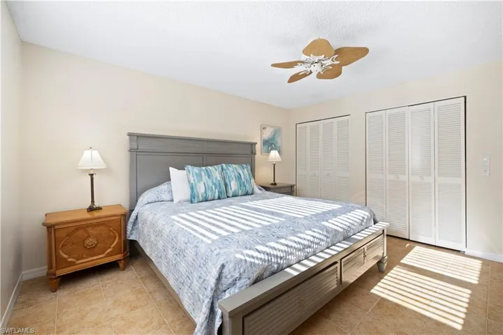 Bedroom featuring two closets, ceiling fan, light tile patterned floors, and a textured ceiling