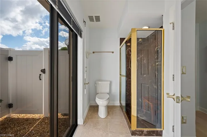 Bathroom with tile patterned flooring, a shower with shower door, and toilet