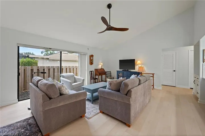 Living room featuring high vaulted ceiling, light hardwood / wood-style floors, and ceiling fan