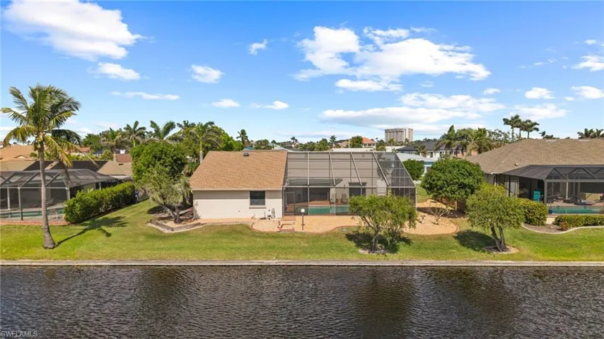 Back of property with a lanai, a lawn, and a water view