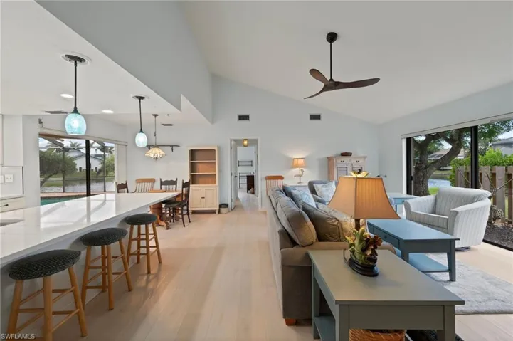 Living room with ceiling fan, high vaulted ceiling, a wealth of natural light, and light wood-type flooring