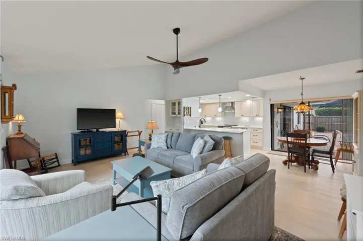 Living room with ceiling fan, high vaulted ceiling, light hardwood / wood-style floors, and sink