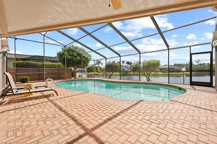View of swimming pool with a water view, a patio, and glass enclosure