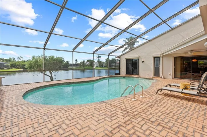 View of swimming pool featuring a water view, a patio, a lanai, and ceiling fan