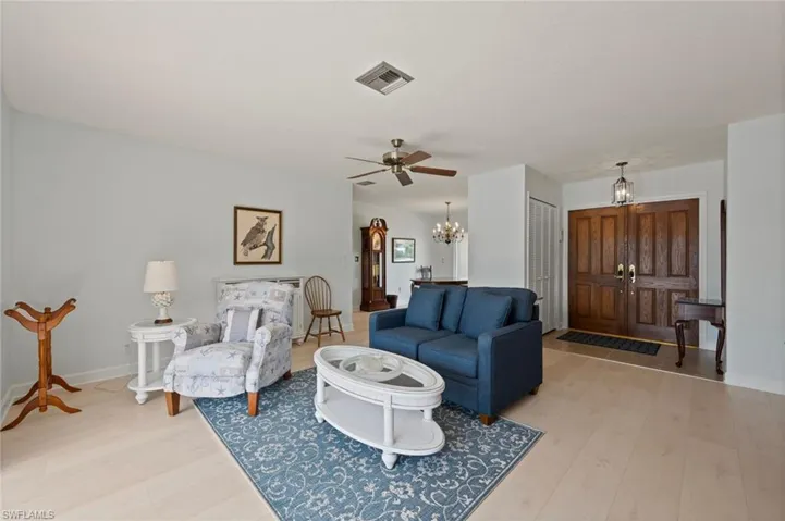 Living room with ceiling fan with notable chandelier and light hardwood / wood-style flooring