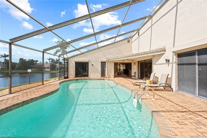 View of pool with a water view, glass enclosure, and a patio area