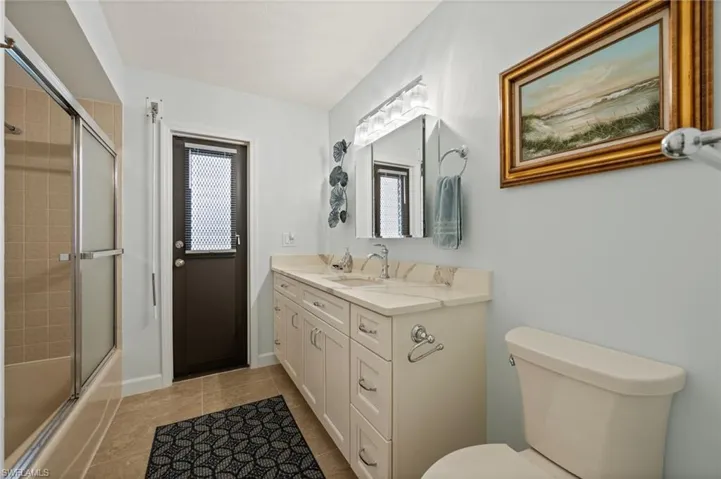 Full bathroom with tile patterned floors, vanity, toilet, and plenty of natural light