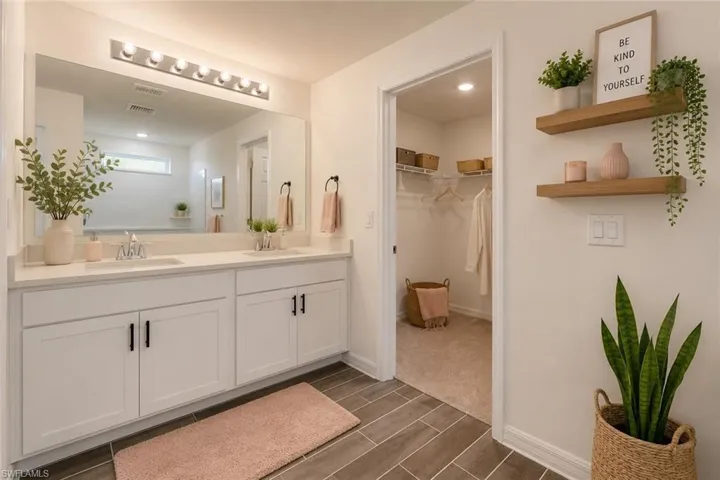 Bathroom featuring a dual vanity with white cabinetry, quartz countertops, and matte black hardware