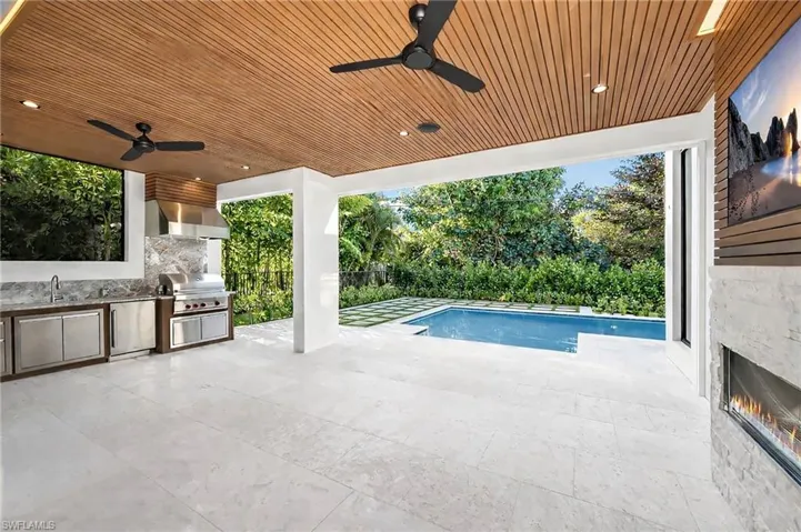 View 1 - Covered lanai with low-voltage lighting, composite woodwork, gas fireplace, and summer kitchen.