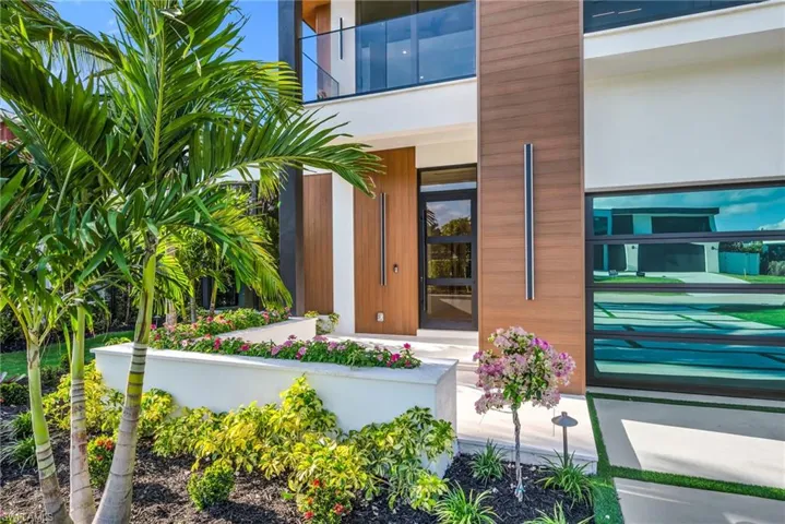 Entryway framed in custom composite woodwork, gracefully lined with raised flower beds.