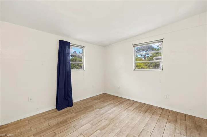 Unfurnished room with light wood-style flooring, baseboards, and lofted ceiling
