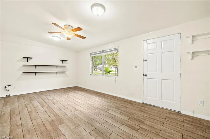 Unfurnished living room featuring ceiling fan, wood finished floors, and baseboards