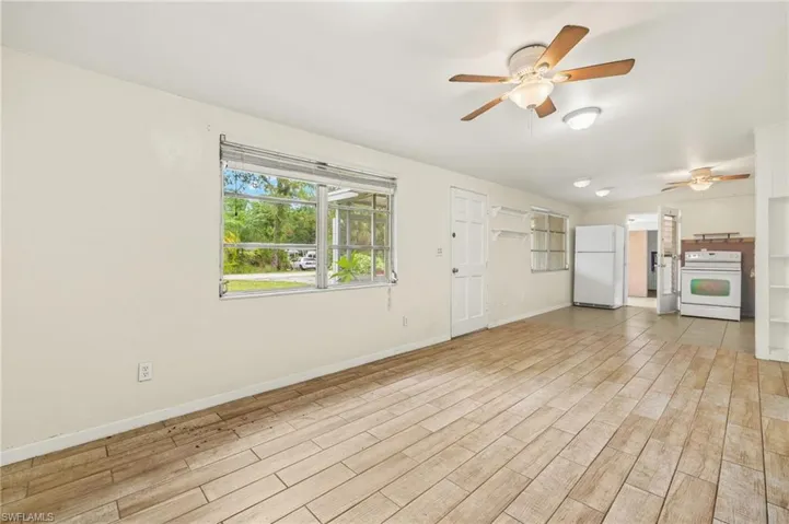 Unfurnished living room with a ceiling fan, wood finished floors, and baseboards