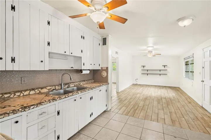 Kitchen featuring a sink, ceiling fan, decorative backsplash, and white cabinetry