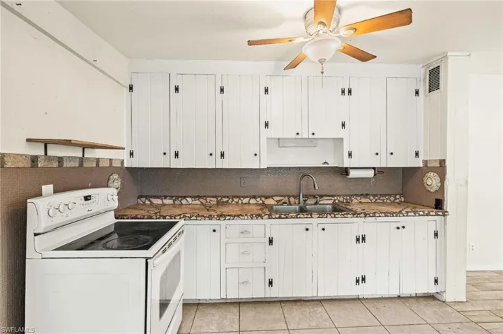 Kitchen with electric range, a sink, white cabinetry, and ceiling fan
