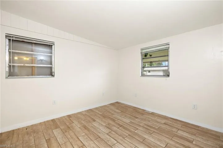 Unfurnished room with wood finished floors, vaulted ceiling, and baseboards