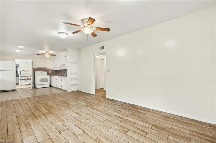 Unfurnished living room featuring a ceiling fan, light wood-style flooring, and baseboards