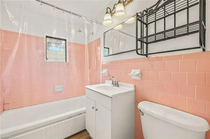 Full bathroom with tile walls, vanity, toilet, and shower / bathtub combination with curtain