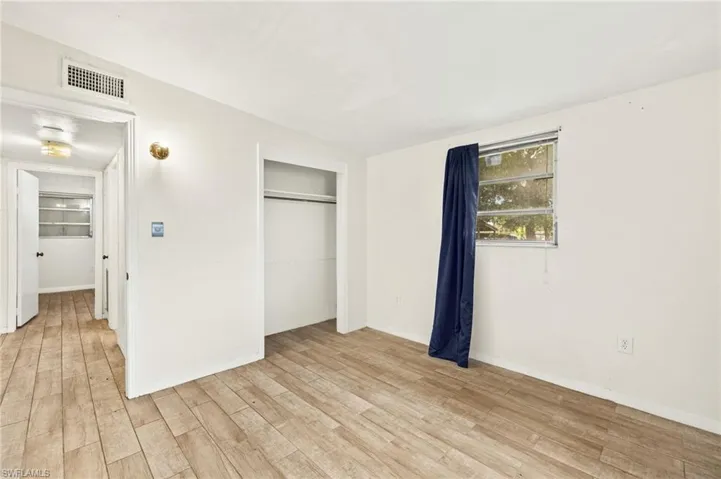 Unfurnished bedroom featuring light wood-type flooring, a closet, and baseboards