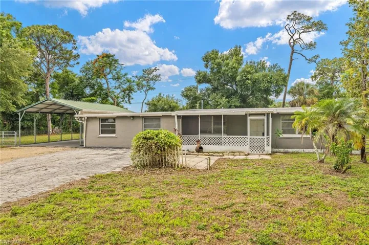 Ranch-style house with stucco siding, a sunroom, a front yard, metal roof, and driveway