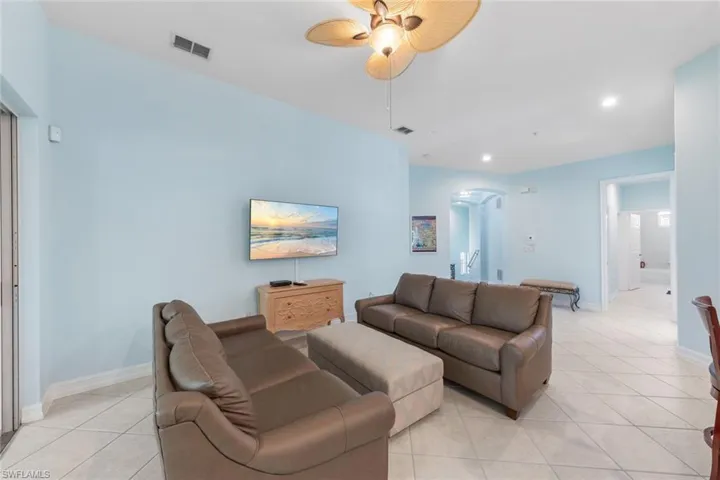 Living room with light tile patterned floors and ceiling fan