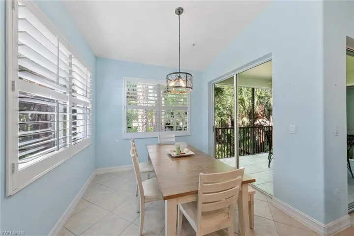 Tiled dining space featuring a wealth of natural light, a notable chandelier, and vaulted ceiling