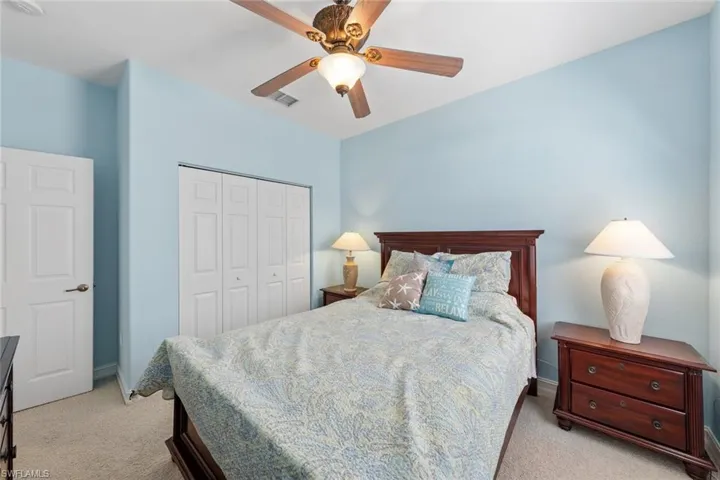 Bedroom with light colored carpet, ceiling fan, and a closet