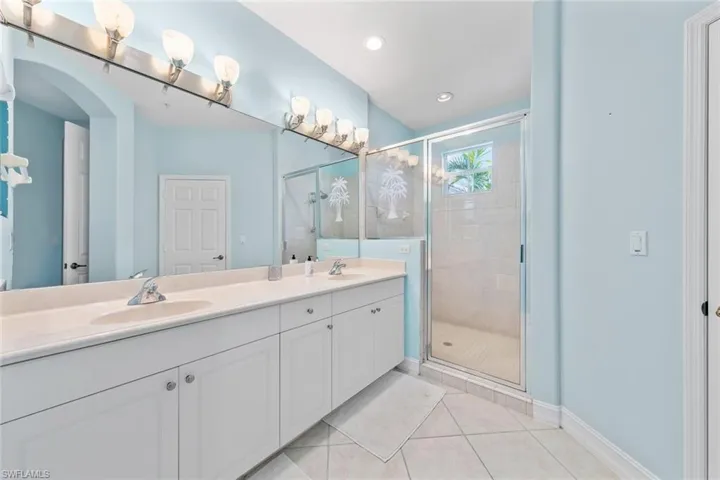 Bathroom featuring a shower with door, vanity, and tile patterned floors