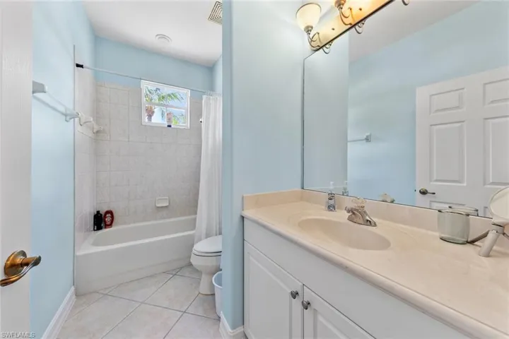 Full bathroom featuring shower / bathtub combination with curtain, tile patterned flooring, toilet, and vanity