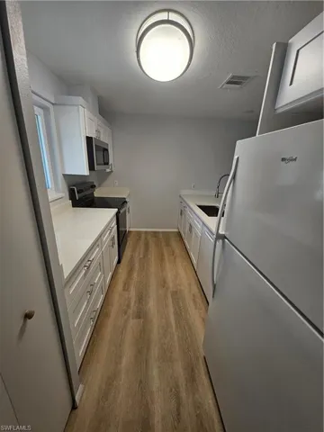 Kitchen with fridge, sink, range, and white cabinets