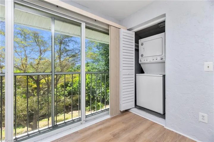 Clothes washing area featuring stacked washer and dryer and light hardwood / wood-style flooring