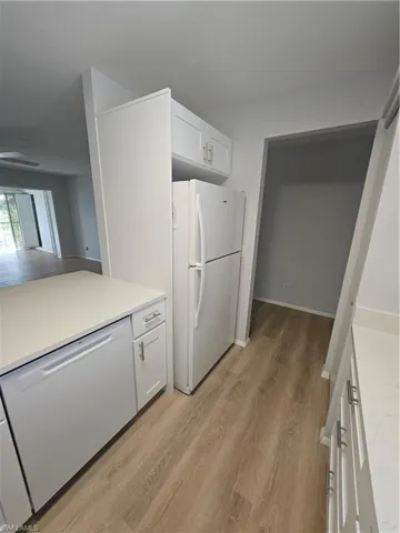 Kitchen featuring white cabinets, light wood-type flooring, dishwasher, and white refrigerator