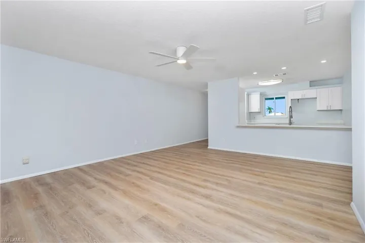 Unfurnished living room featuring ceiling fan, a textured ceiling, and light wood-type flooring