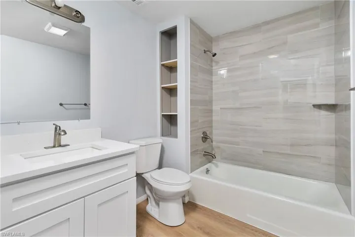 Full bathroom featuring hardwood / wood-style flooring, vanity, toilet, and tiled shower / bath combo