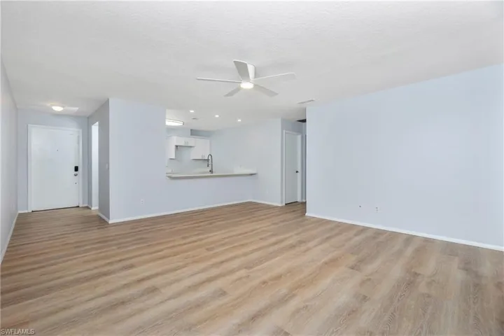 Unfurnished living room with sink, a textured ceiling, light hardwood / wood-style flooring, and ceiling fan