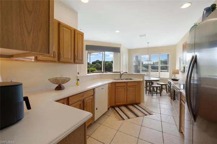 Kitchen featuring hanging light fixtures, stainless steel appliances, kitchen peninsula, sink, and light tile flooring