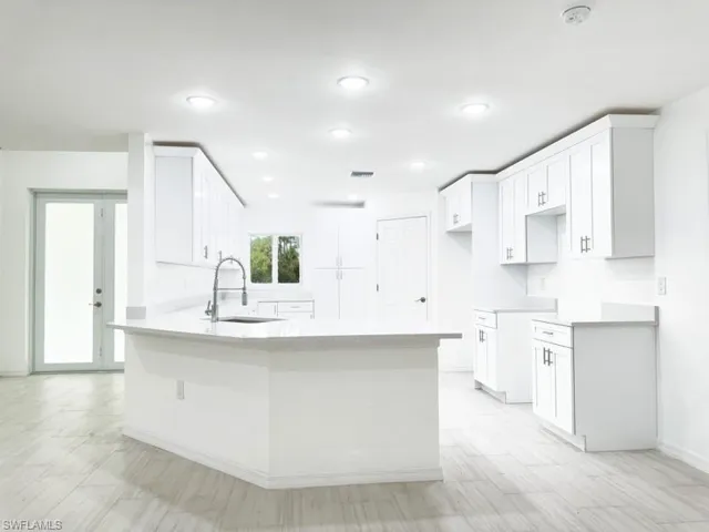 Kitchen with white cabinetry, sink, and kitchen peninsula