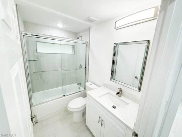 Full bathroom featuring vanity, toilet, and combined bath / shower with glass door
