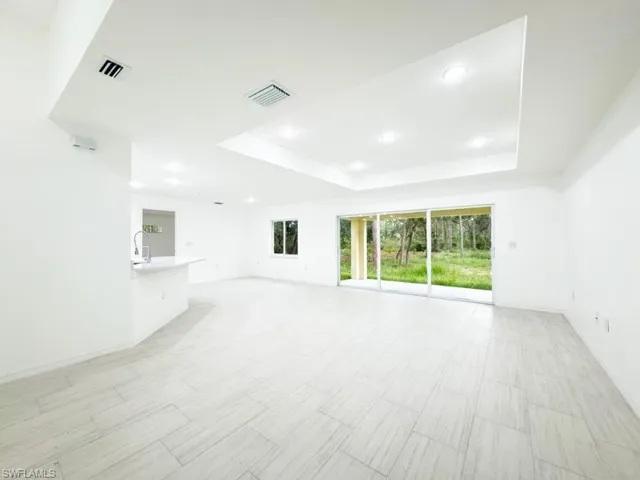 Unfurnished living room featuring sink and a tray ceiling