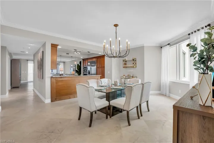 Tiled dining space featuring a notable chandelier, crown molding, and a wealth of natural light