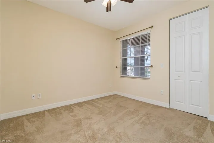 Bedroom # 4, view to the street/amenities. light colored carpet and ceiling fan.