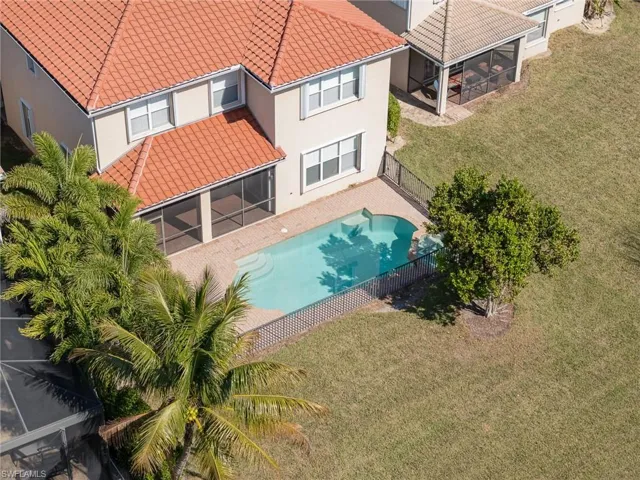 Aerial view of swimming pool with plenty of sunshine and a pristine landscape.