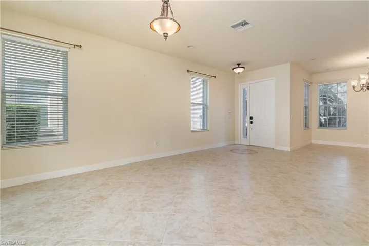 Tiled empty room with a notable chandelier
