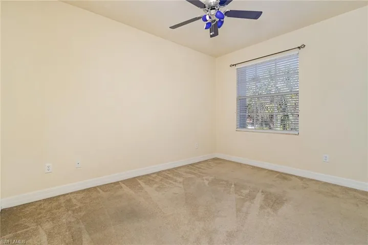 Bedroom # 5, view to the street/amenities. light colored carpet and ceiling fan.