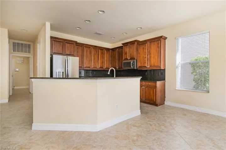 Kitchen featuring sink, dark stone counters and back Splash, stainless steel appliances, a kitchen breakfast bar with sink and Cherrywood color cabinets.