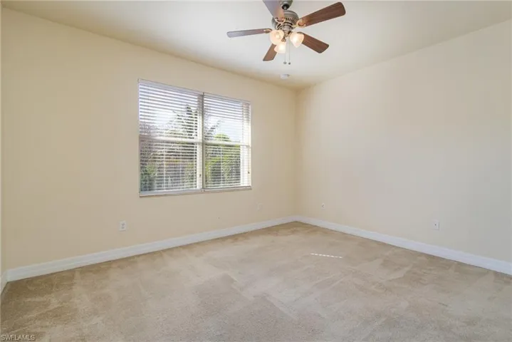 Bedroom # 3, view to the preserve and pool light colored carpet and ceiling fan.